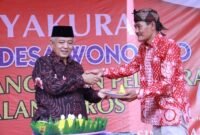 Caption. Bupati Malang H.M Sanusi saat memberikan potongan tumpeng pada Kepala Desa Wonorejo Singosari 