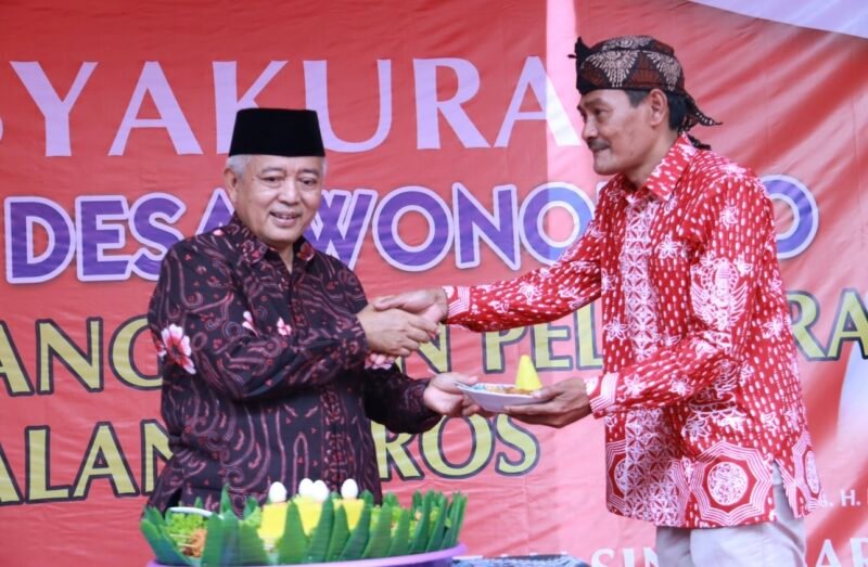 Caption. Bupati Malang H.M Sanusi saat memberikan potongan tumpeng pada Kepala Desa Wonorejo Singosari 