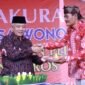 Caption. Bupati Malang H.M Sanusi saat memberikan potongan tumpeng pada Kepala Desa Wonorejo Singosari 