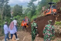 Foto : Anggota Polres Maang bersama TNI dan warga bersikan material tanah longsor