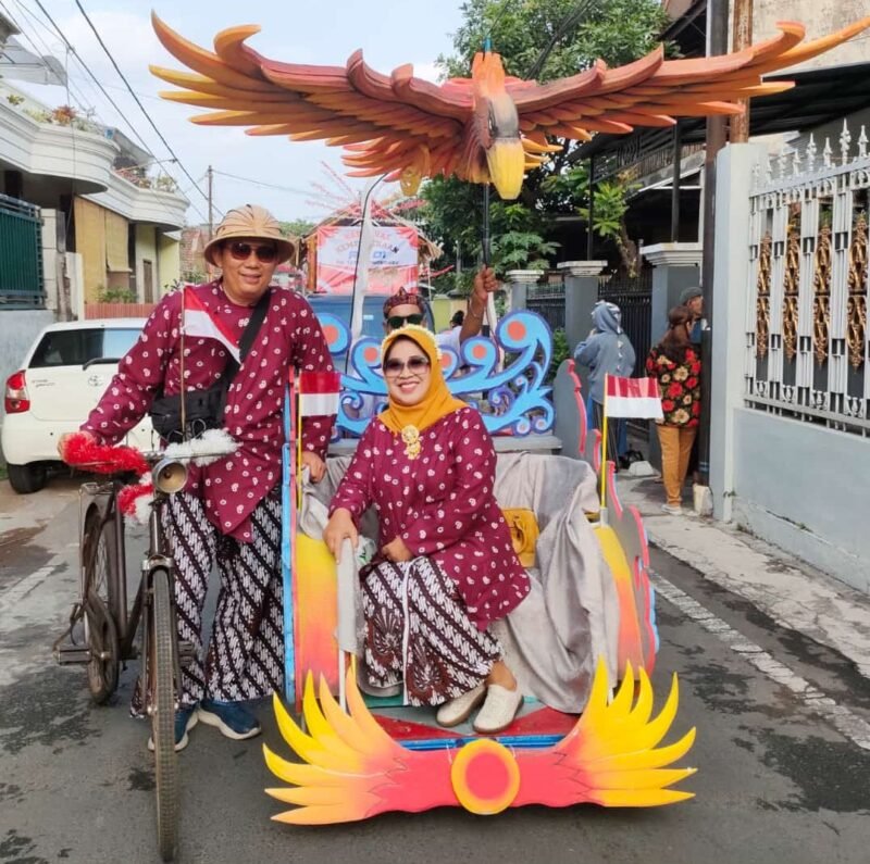 Foto : Bu RW 15 Intiarni Hadi Sumanto menaiki becak dengan maskot Garuda bersama Ketua RW 15 Kelurahan Lowokwaru Hadi Sumanto