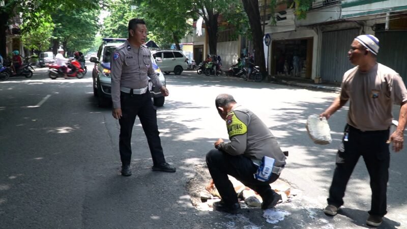 Ket foto. Petugas Kepolisian Resor Pasuruan saat memperbaiki jalan yang berlubang 
