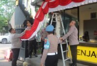 Personel dari Polres Pasuruan sedang melaksanakan giat pemasangan umbul-umbul merah putih jelang HUT ke-80 RI (dok. Ist)