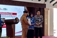 Ket foto. Bupati Malang H.M Sanusi didampingi Plt Kepala Dinas Lingkungan hidup saat menyerahkan  penghargaan lingkungan hidup pada Kepala Sekolah SMPN I Pakis, Dra. Nurus Solehati